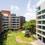 Complejo residencial moderno con jardines, áreas comunes y arquitectura de ladrillo y vidrio.
