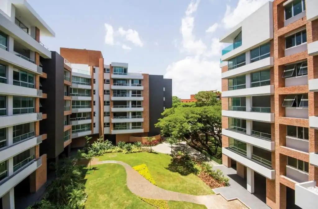 Complejo residencial moderno con jardines, áreas comunes y arquitectura de ladrillo y vidrio.