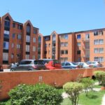 Conjunto residencial en Bogotá con fachadas de ladrillo, jardín y parqueadero ordenado.