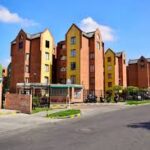 Conjunto residencial moderno con fachadas coloridas y calles limpias en día soleado.